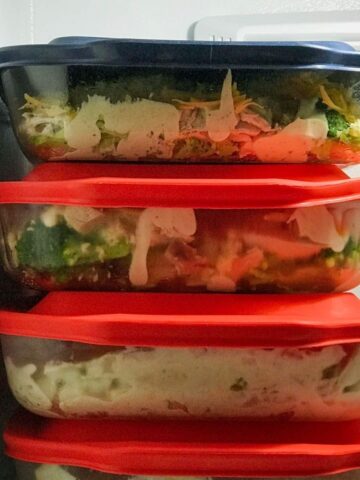 stack of pyrex dishes with lids filled with casseroles in the freezer.