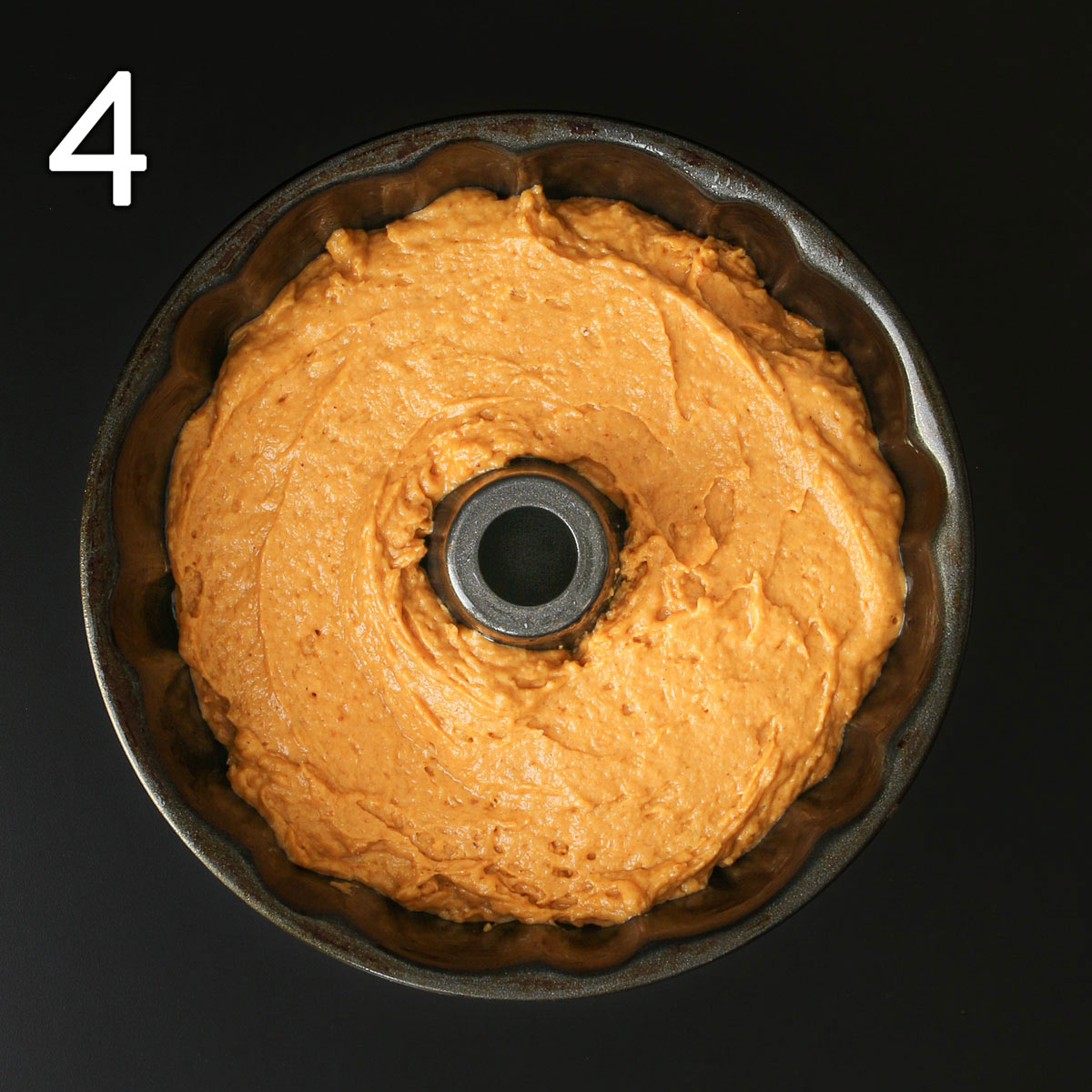 pumpkin cake batter spooned into bundt cake pan.